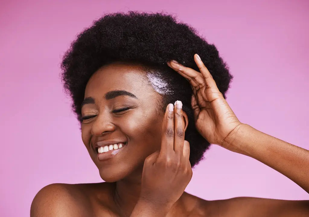 Smiling woman with natural afro hair highlighting the benefits of deep conditioning treatments
