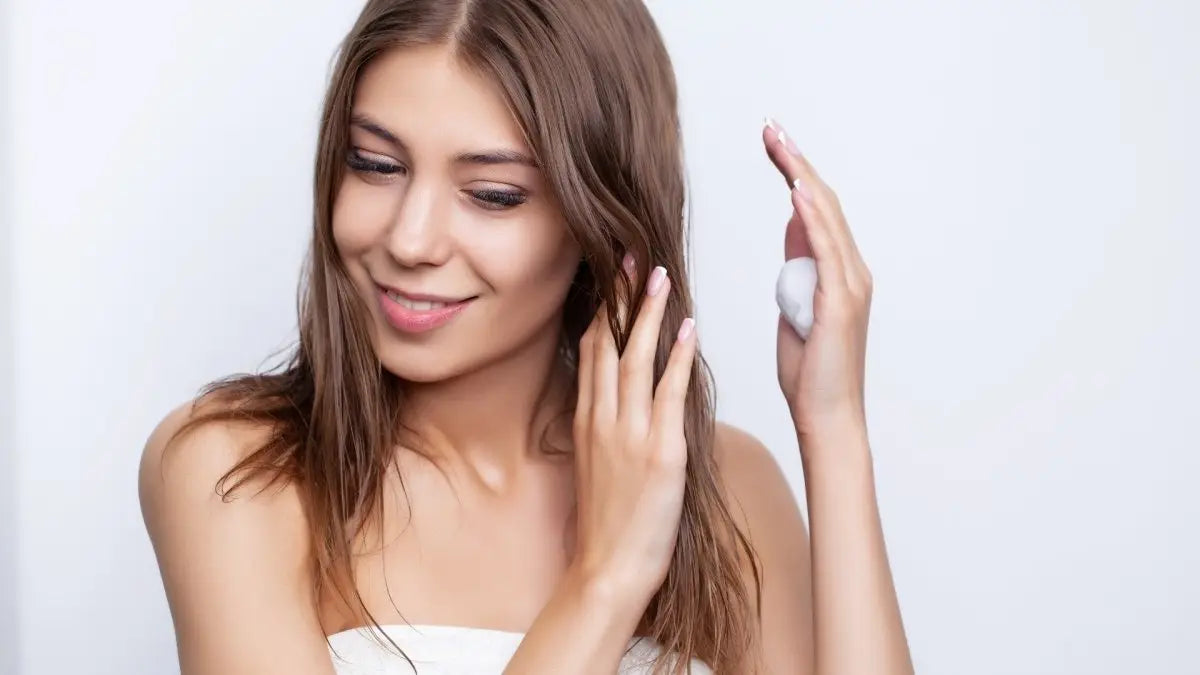 Young woman smiling while using Nak Signatures Volume Shampoo for greasy hair tips.