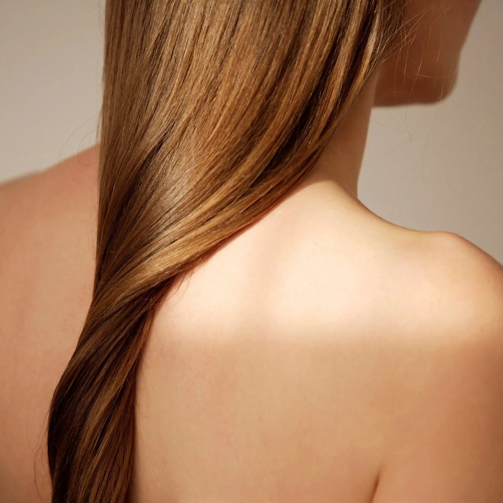 Long, smooth brown hair over a bare shoulder for maintaining hair health in your routine.
