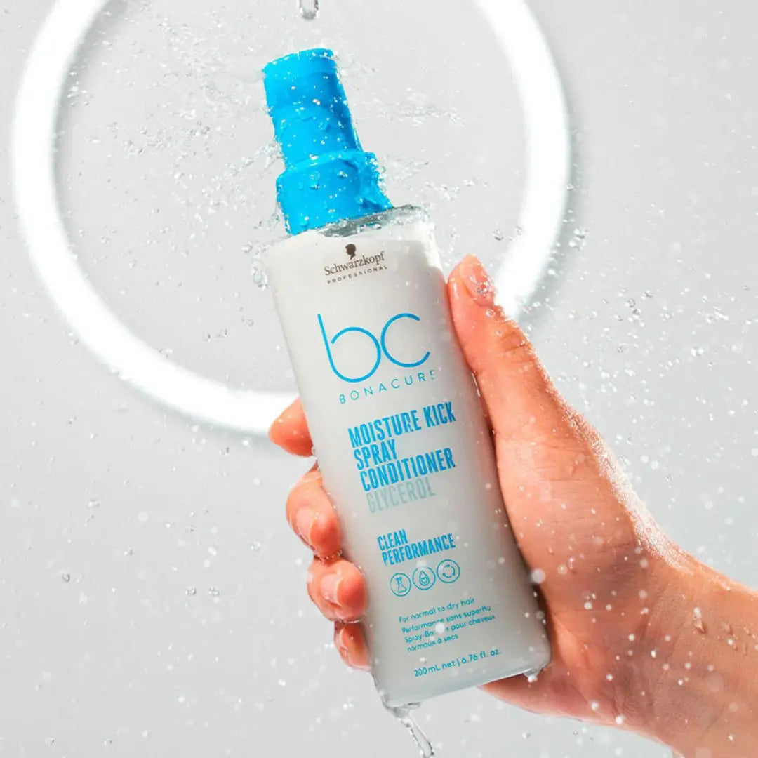 Hand holding Schwarzkopf Moisture Kick conditioner bottle under water droplets.