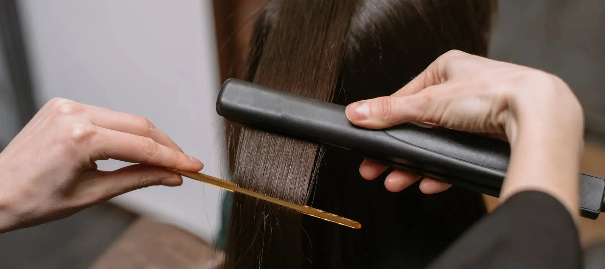Hair straightener smoothing long dark hair in a South Africa keratin treatments guide.