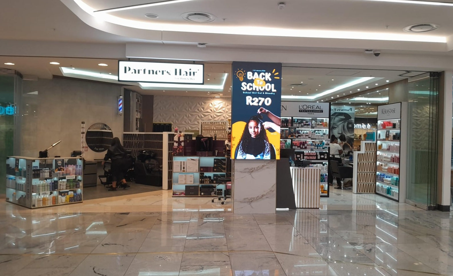Mall interior with a hair salon sign and promotional banner.