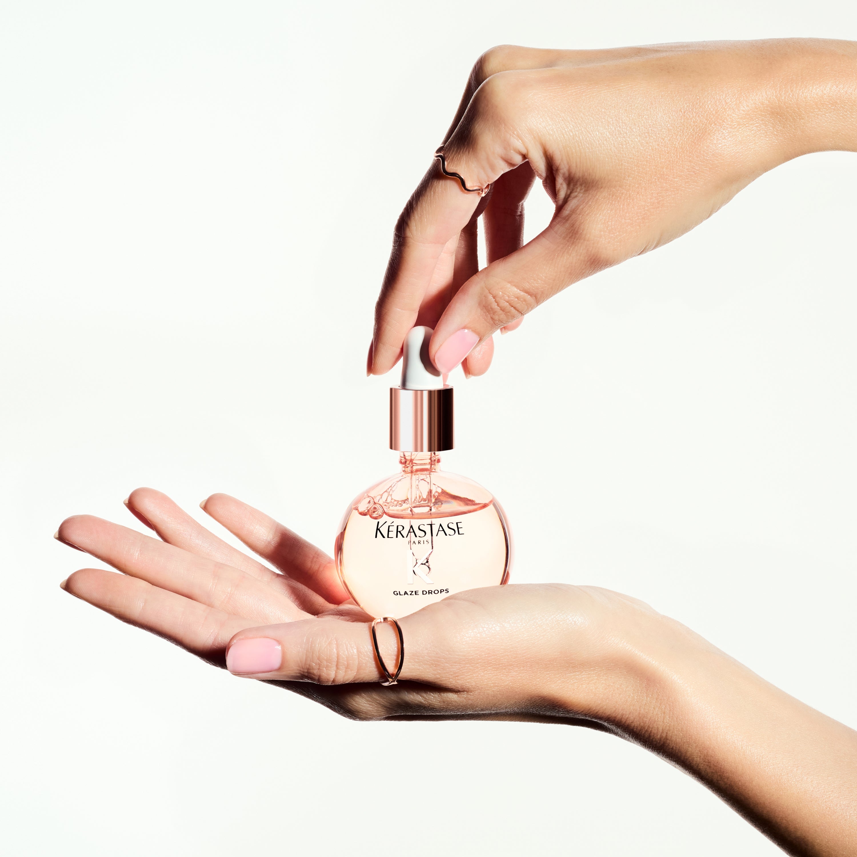 KERASTASE Gloss Absolu Glaze Drops: Anti-Frizz Hair Oil for Shiny, Smooth Hair. Featured product in hand with ring.