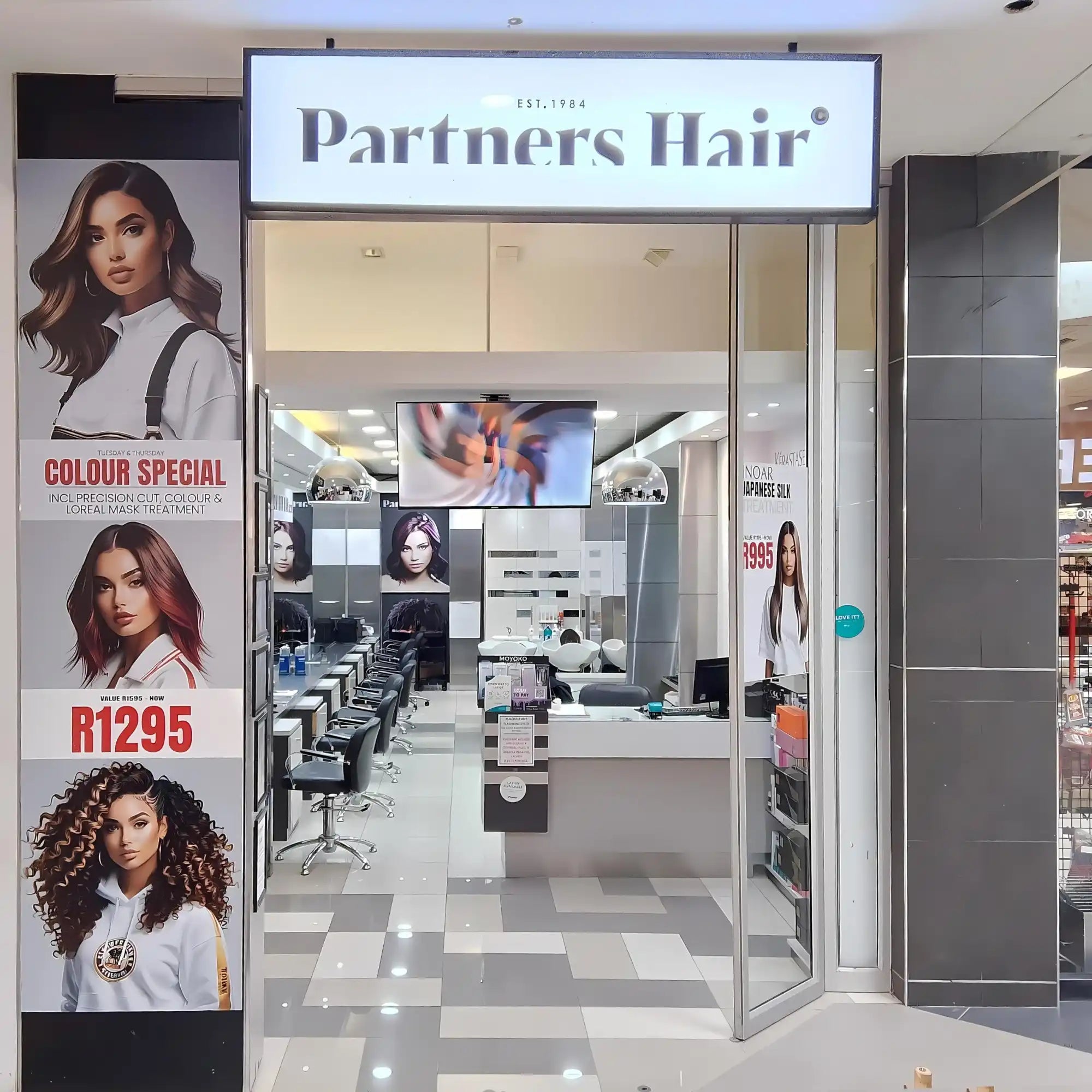 Hair salon storefront with ’Partners Hair’ signage and promotional posters.