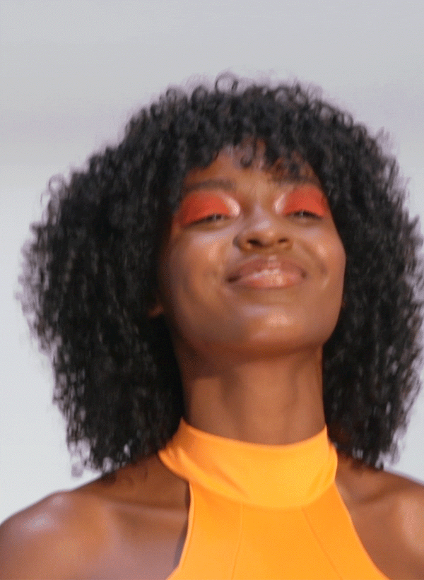 K18 hair repair: Woman with curly hair, using leave-in mask for healthy, strong locks. K18 results for African American hair.