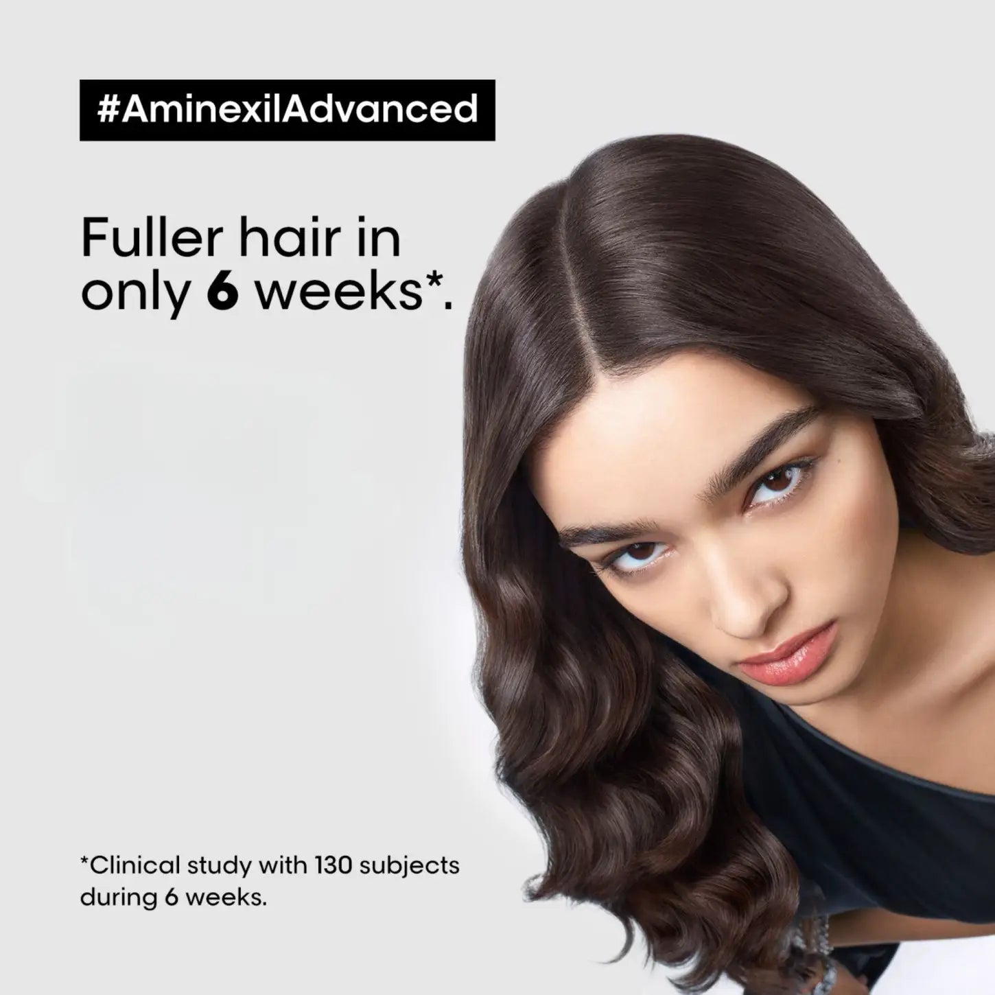 Woman with long wavy hair using Serioxyl Advanced Aminexil from Loreal Aminexil Kit