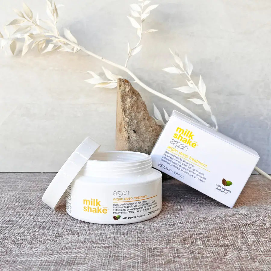 Milkshake Argan Deep Treatment for hair in an open white jar with product box on gray surface