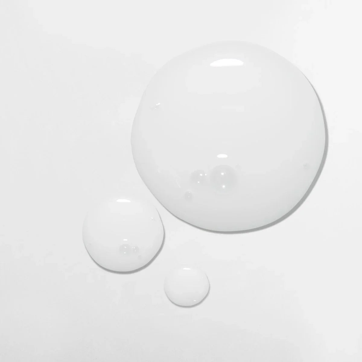 Three white, glossy droplets of Mizani Scalp Care Calming Lotion 118ml