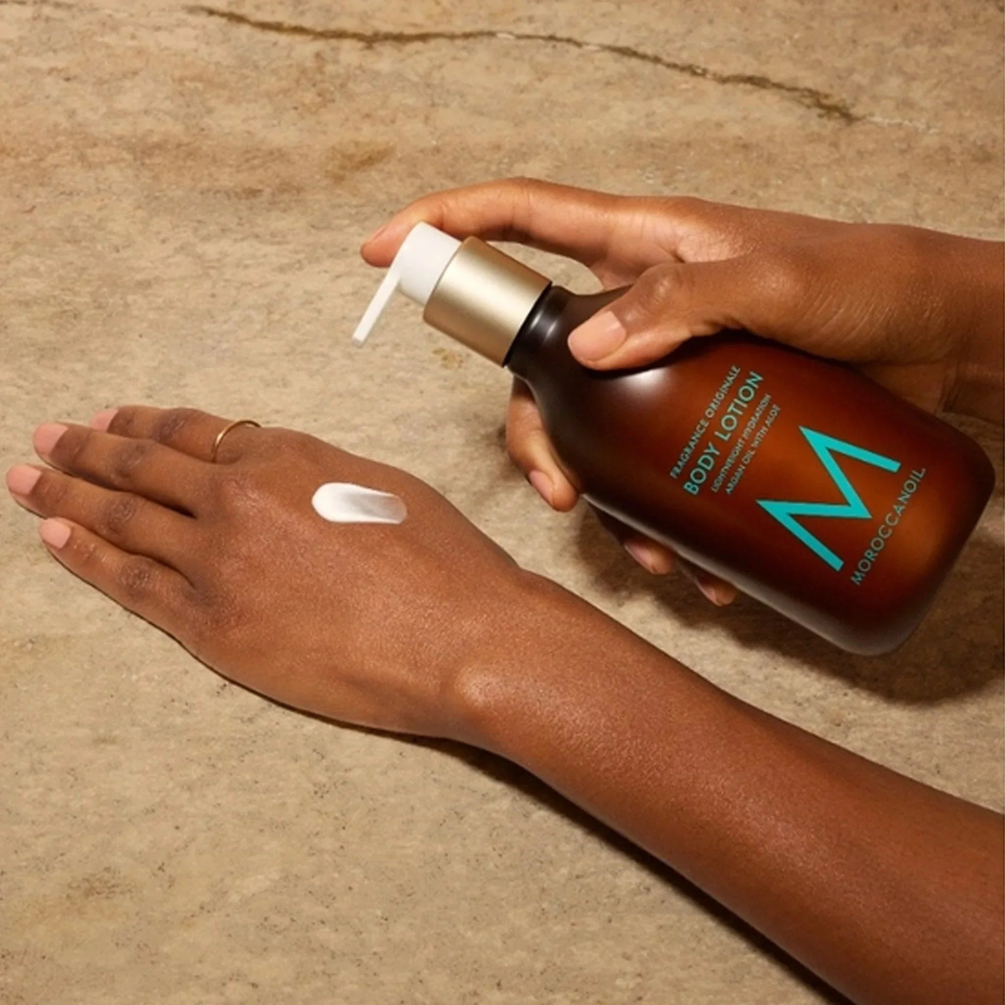 Moroccanoil Body Lotion Fragrance Originale: Woman applying argan oil lotion for dry skin hydration.