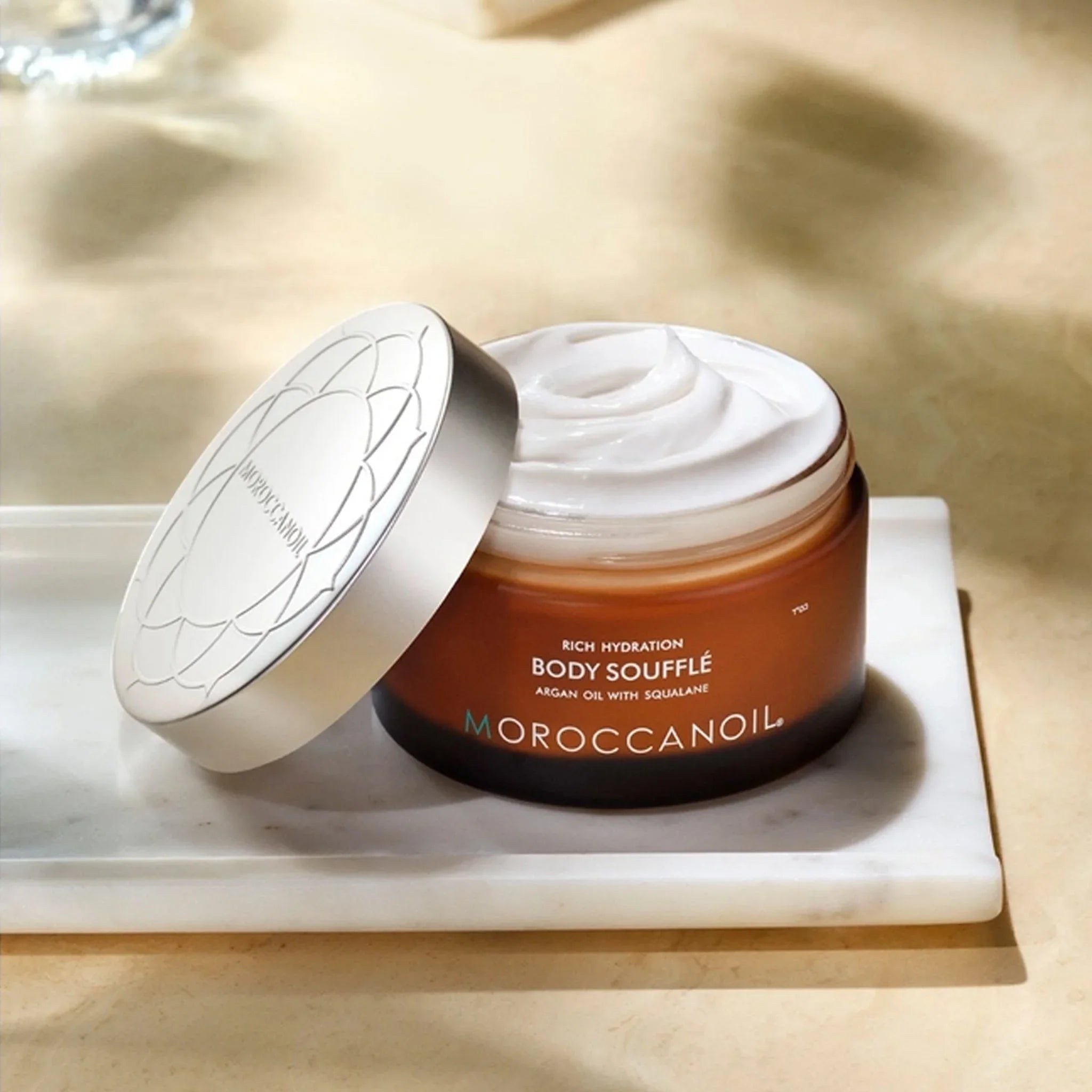 Moroccanoil Body Soufflé: Open jar of hydrating cream with Argan Oil for intense skin hydration.