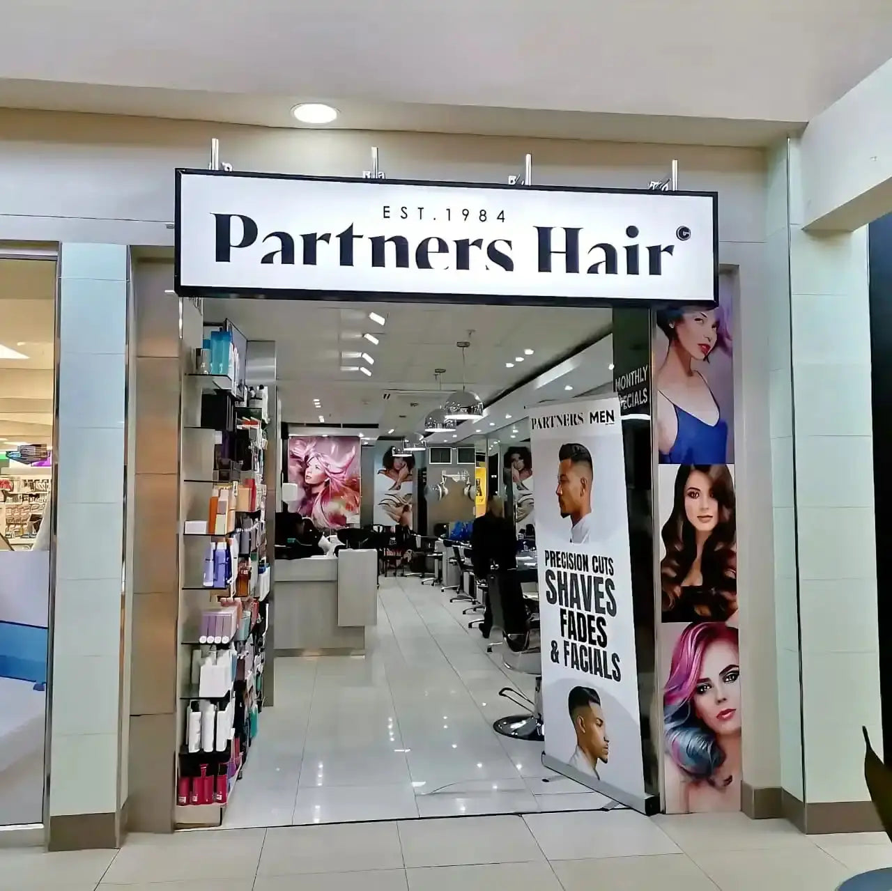 Partners Hair salon storefront with its signage and promotional posters.