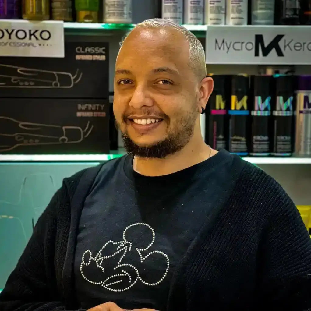 A smiling person wearing a black sweater with a Mickey Mouse design.