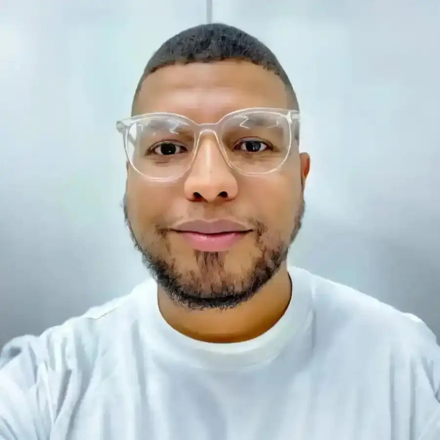 A person wearing clear-framed glasses and a white t-shirt.