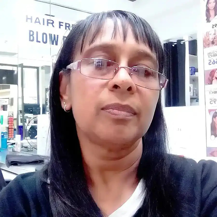 A person wearing glasses and a black sweater with straight dark hair.