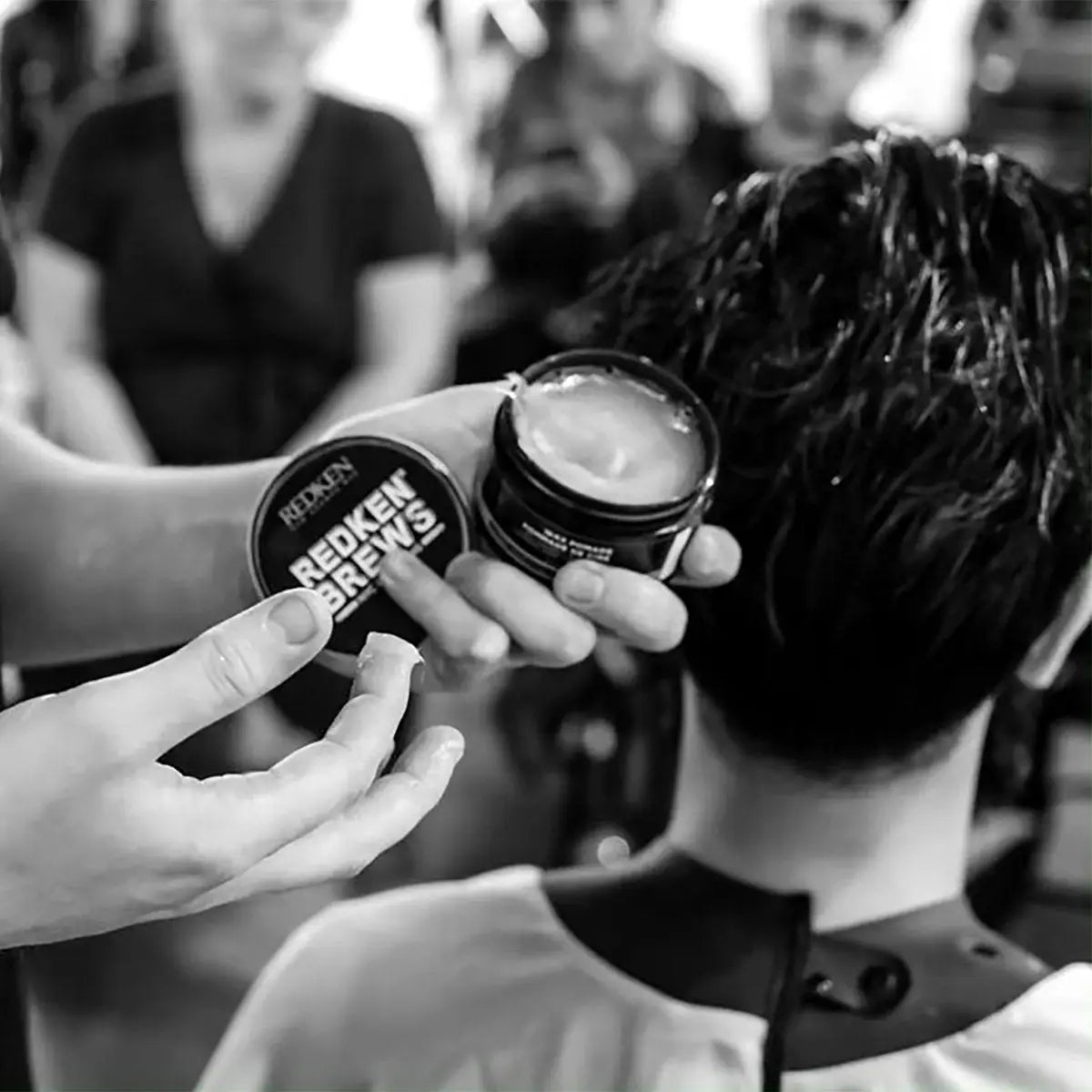 Redken Brews Maneuver Cream Pomade being applied in a salon setting for sleek hair styling