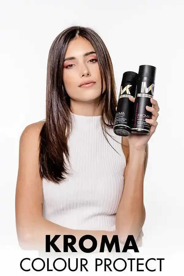 Woman with long dark hair holding hair product bottles in a promotional image for Kroma Colour Protect.