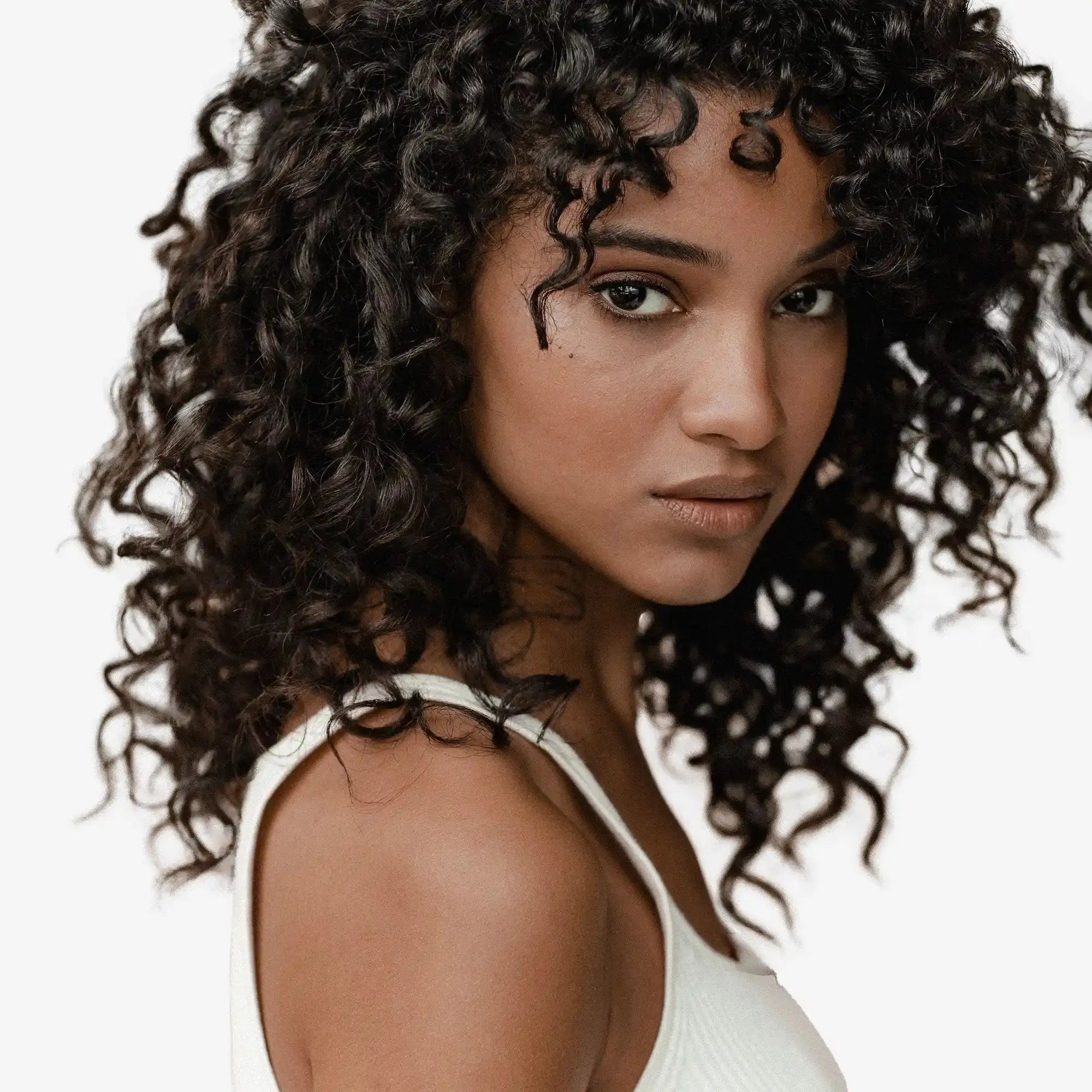 Woman with voluminous curly dark hair and a white top.