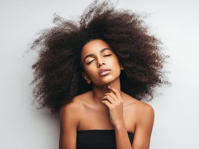 Woman with natural curly hair posing with eyes closed, showcasing fabulous curls.