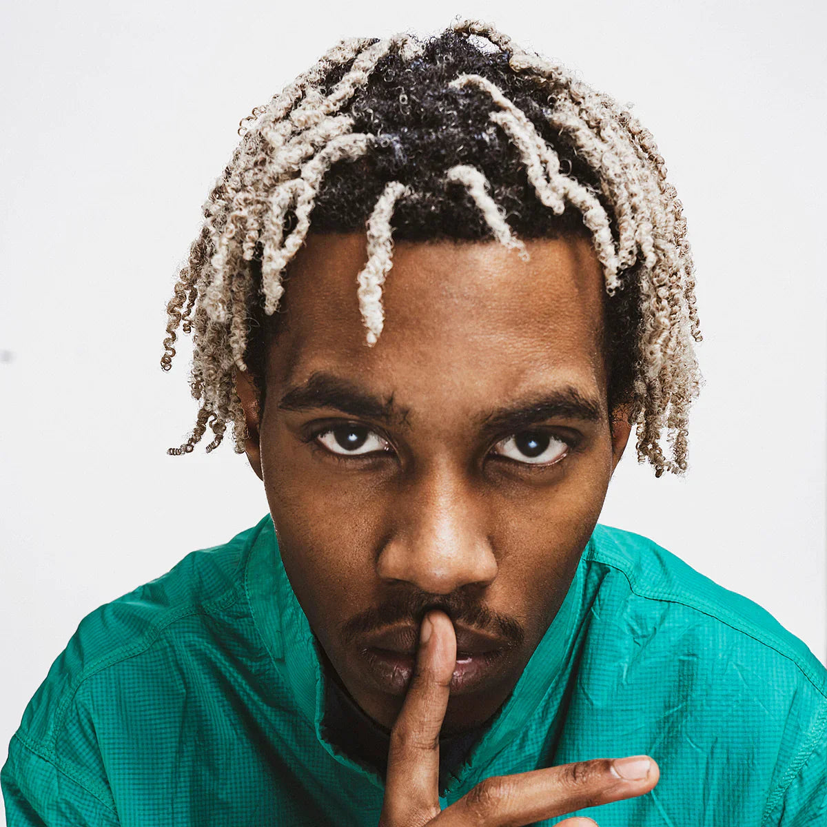 Young man with two-toned dreadlocks using Reuzel wax for a perfect hairstyle.