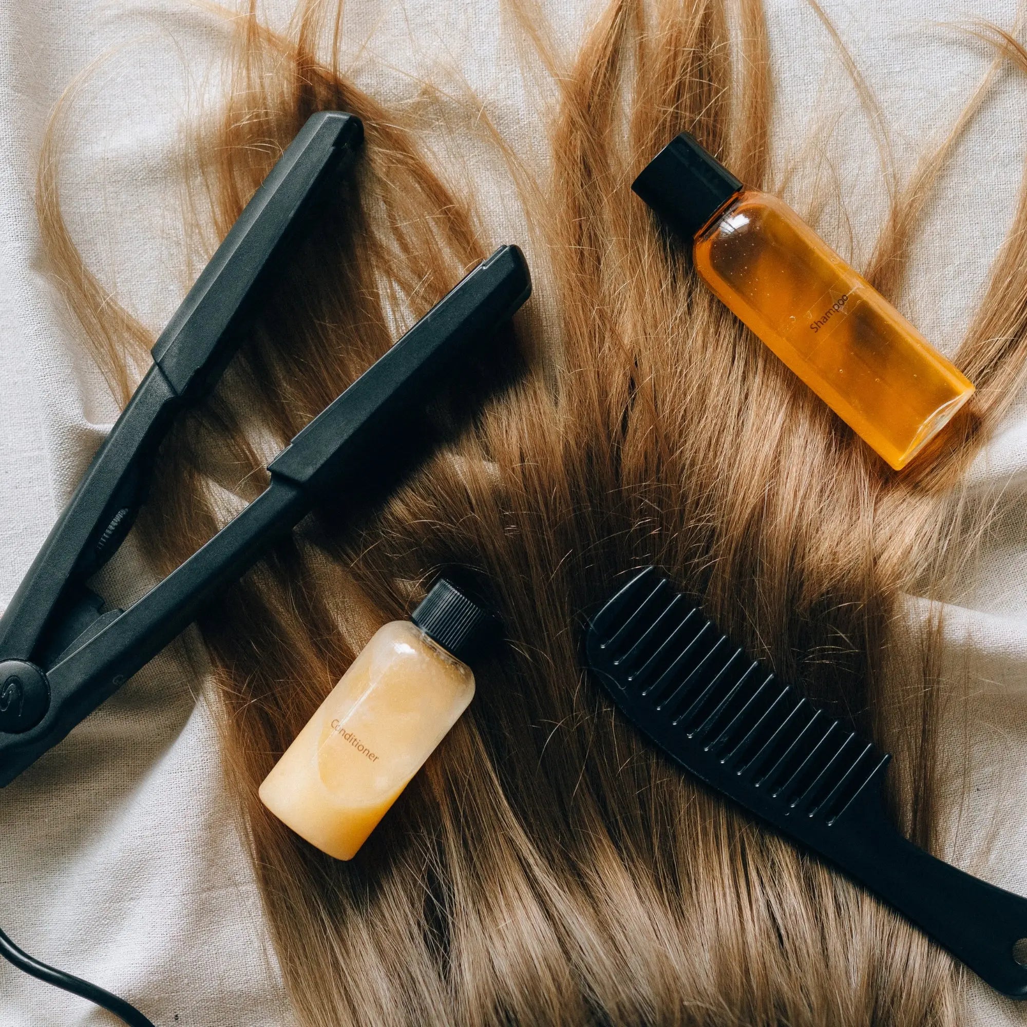 Hair with styling tools and products beside sulfate-free shampoos for color-treated hair.