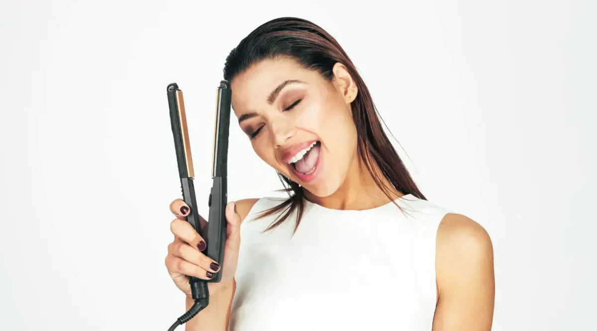 Smiling woman with long dark hair holding flat iron in How to Choose the Perfect Hair Styler.