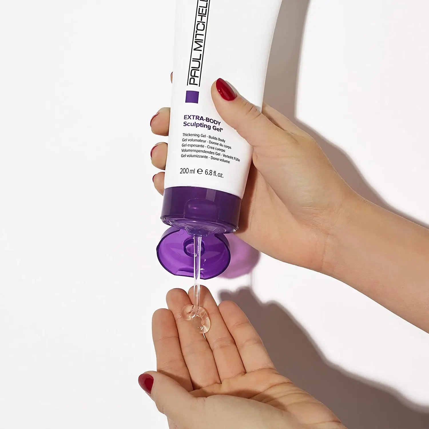 Purple and white Paul Mitchell hair product being dispensed onto a hand