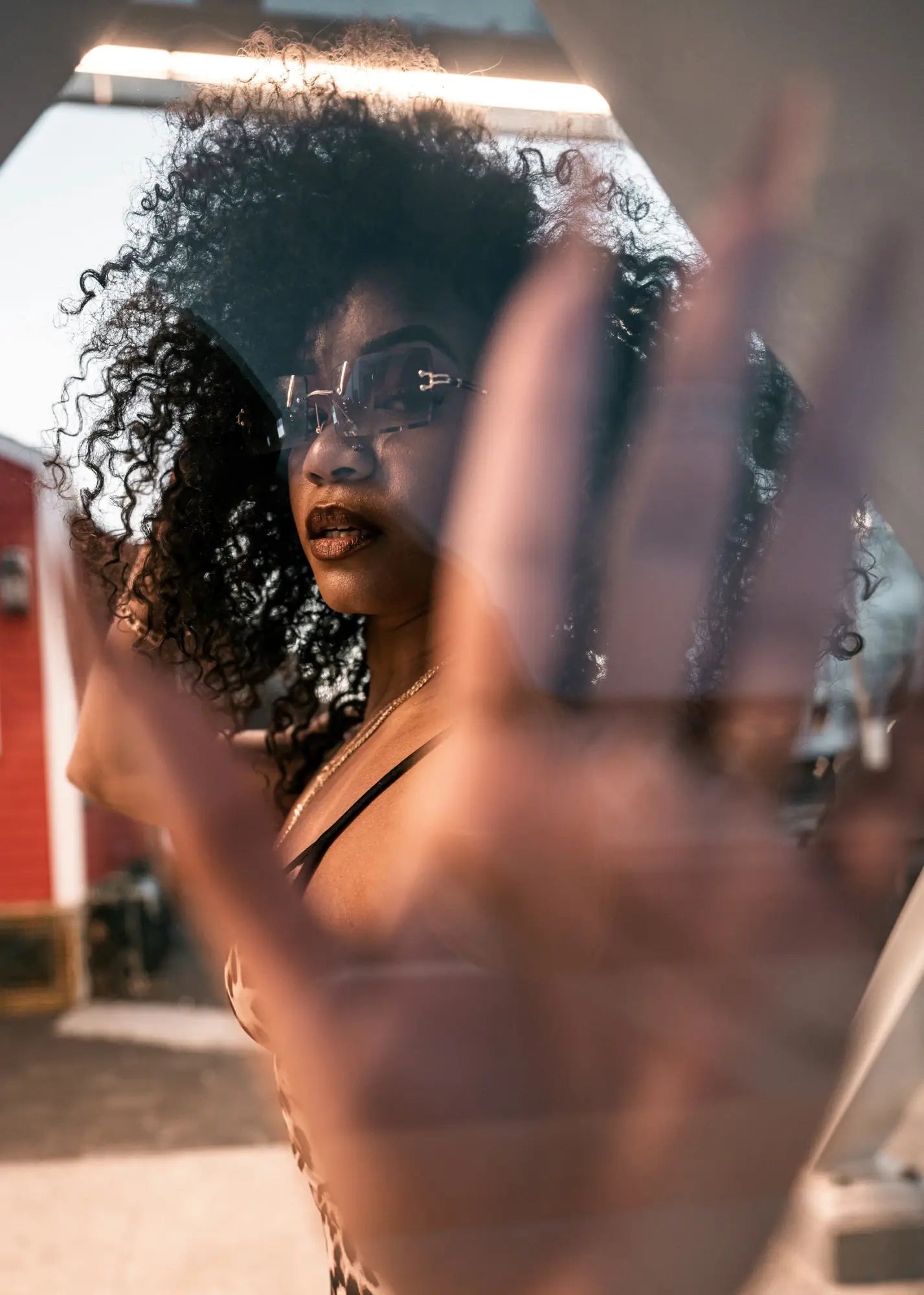 Woman with curly hair looking through glass, exploring her unique curl patterns.