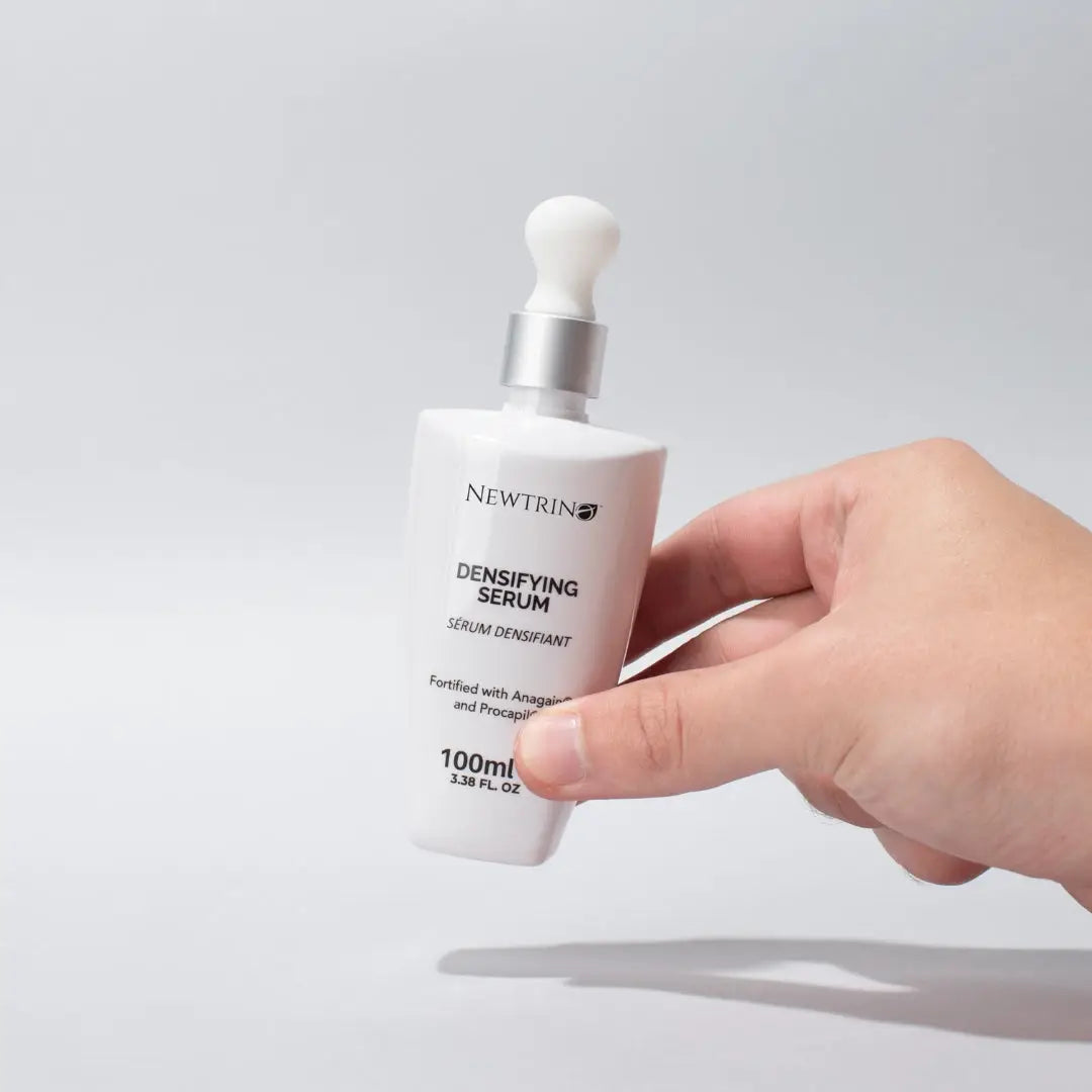 White Newthis Densifying Serum in hand for effective hair care routine and hair growth.