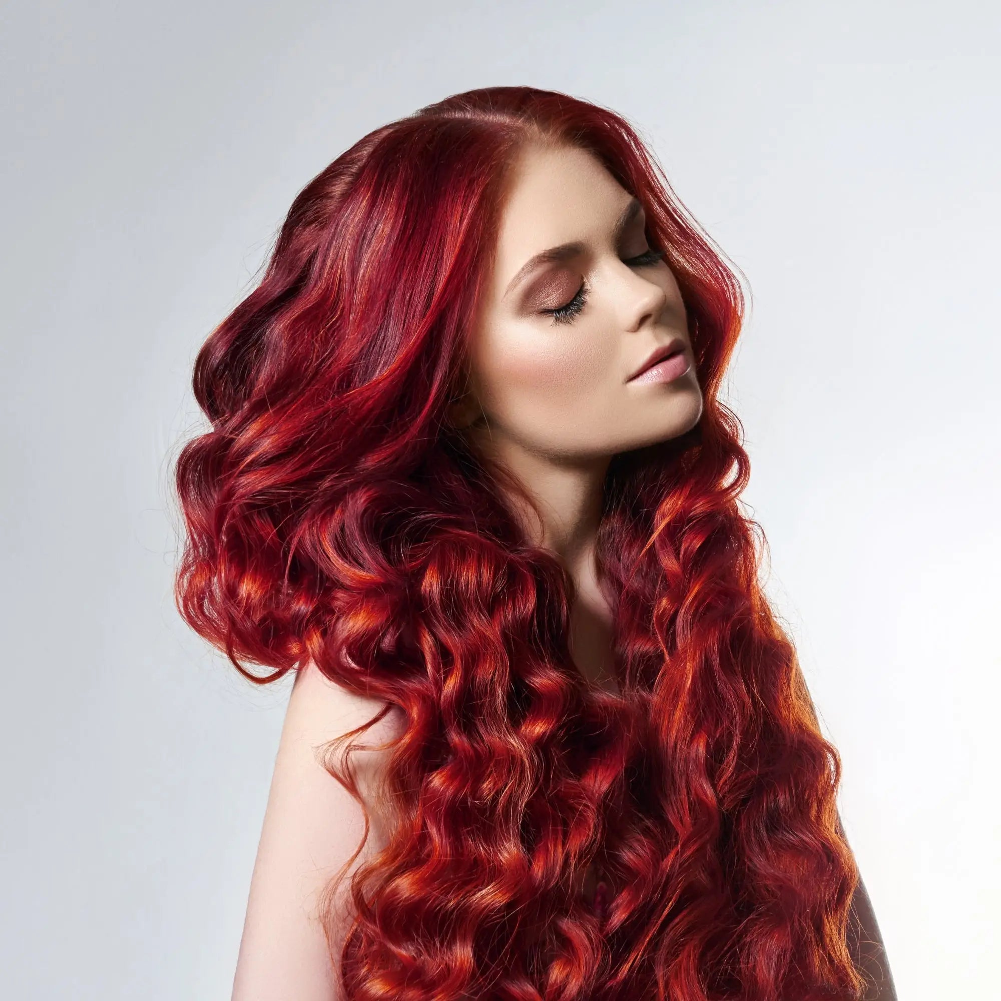 Vibrant red curly hair cascading down a woman’s back at Partners Hair Design.