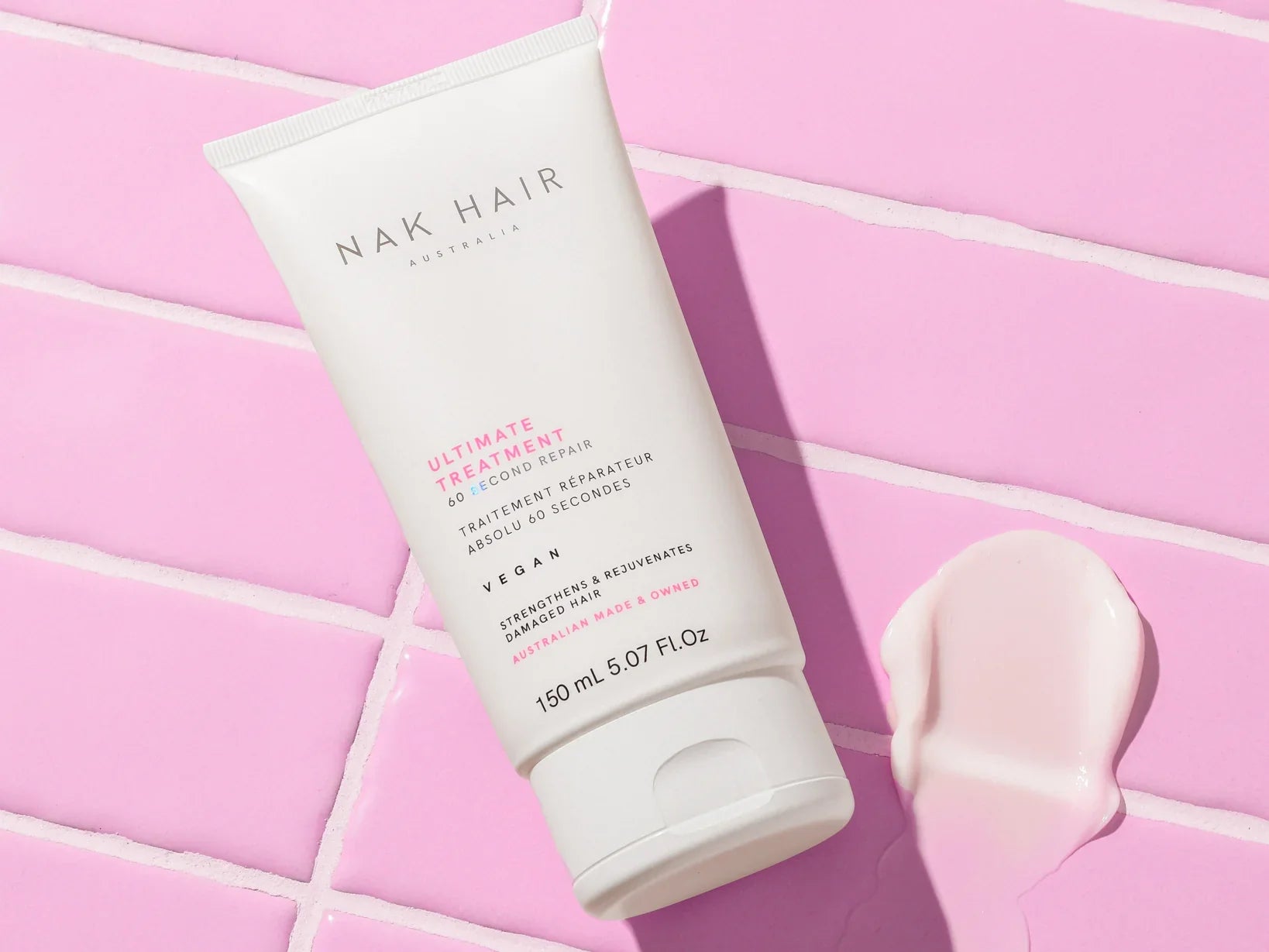 White tube of Nak sulphate-free hair product on a pink surface, showcasing Nak innovation.