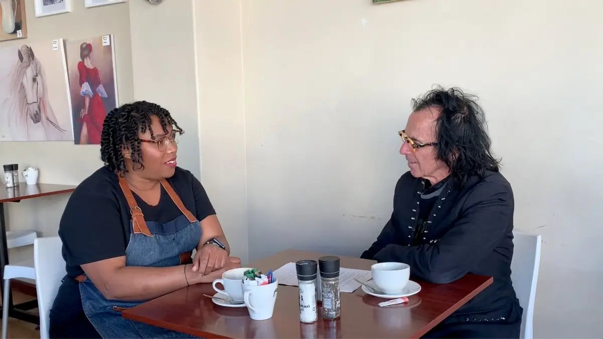 Two people enjoying coffee at Partners Men Cavendish Square, engaging in conversation.