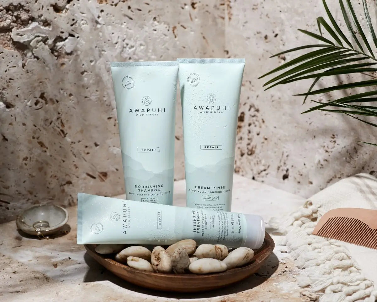 Tubes of Paul Mitchell Awapuhi skincare with stones and palm leaves for healthy hair.