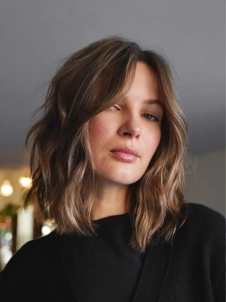 Woman with wavy brown hair in a black top showcasing short hair styling tips.