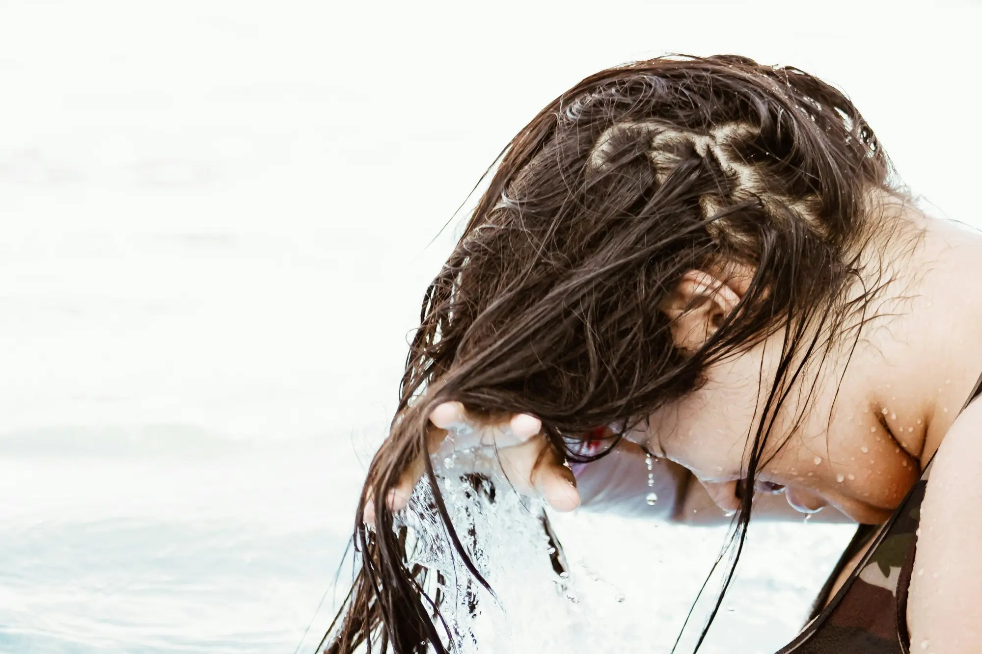 Wet dark hair cascading over a person’s face, showcasing the benefits of sulfate-free shampoo.