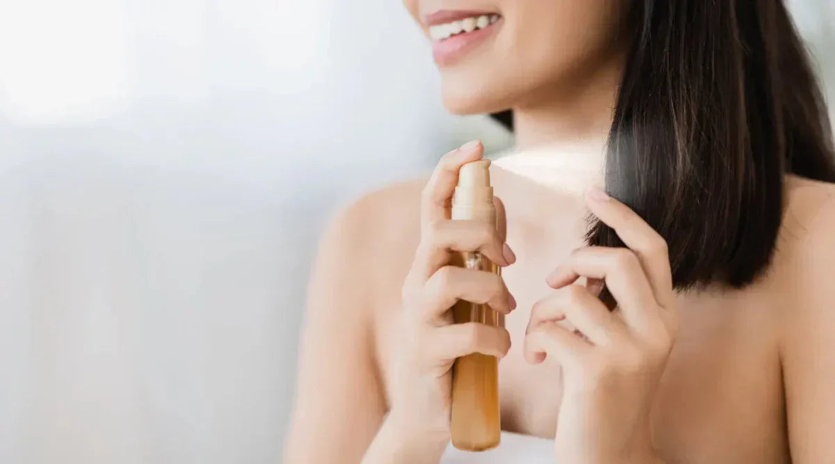 Person holding a fragrance bottle related to minimizing heat damage from heat styling tools.