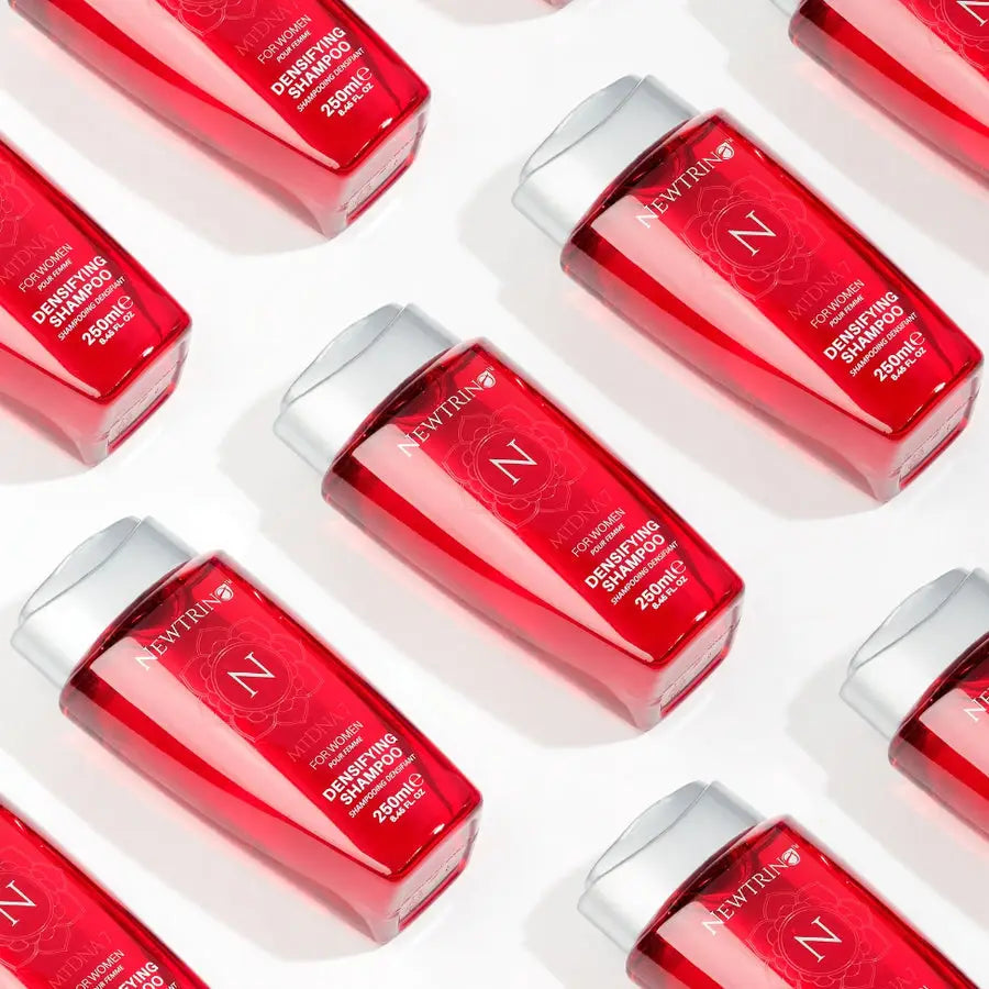 Red cosmetic bottles with white caps, part of a holistic approach to female hair loss.