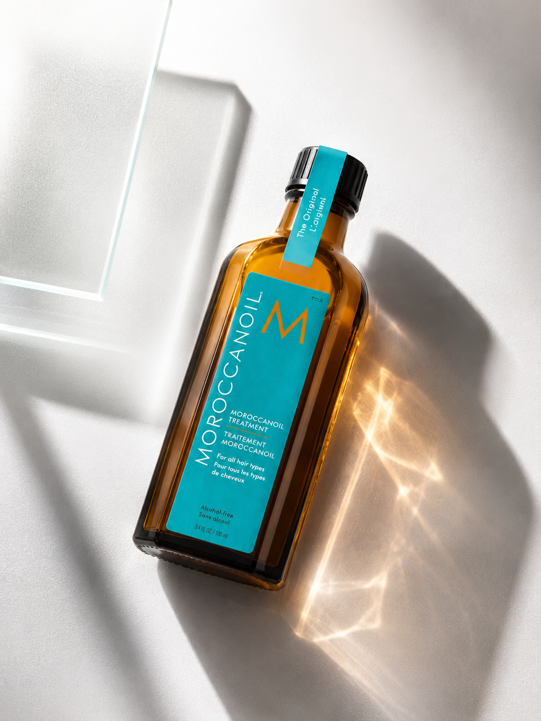 Moroccanoil treatment bottles arranged on a modern surface, showcasing the signature turquoise and amber packaging, ideal for hair nourishment and shine.