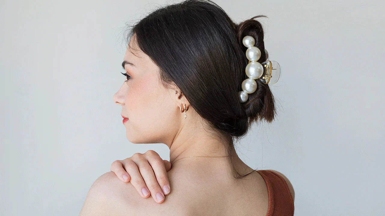 Woman with dark hair in updo, pearl clip, featuring Moyoko detangling brush from Accessories.