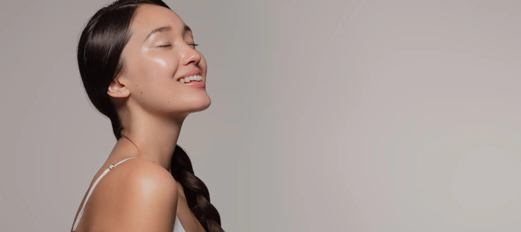 Woman with long dark hair smiling with eyes closed, showcasing Motherkind Collagen benefits.