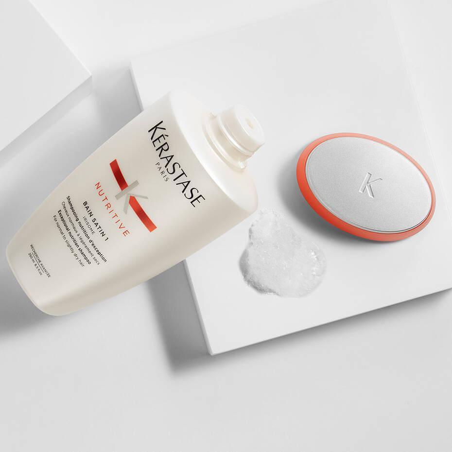 Kerastase dry hair shampoo bottle with spilled product on a white background