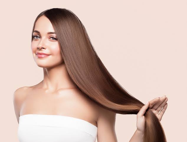 Long, straight brown hair held by a woman’s hand from the Keratin Collection. Brasil Cacau products.