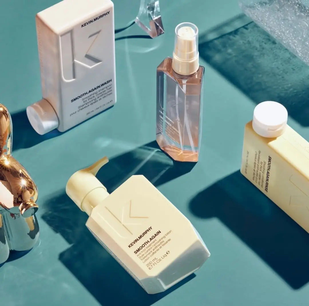 Assorted Kevin Murphy hair products including shampoo, conditioner, and spray on a blue surface