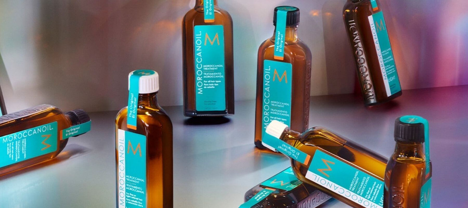 Moroccanoil treatment bottles arranged on a modern surface, showcasing the signature turquoise and amber packaging, ideal for hair nourishment and shine.