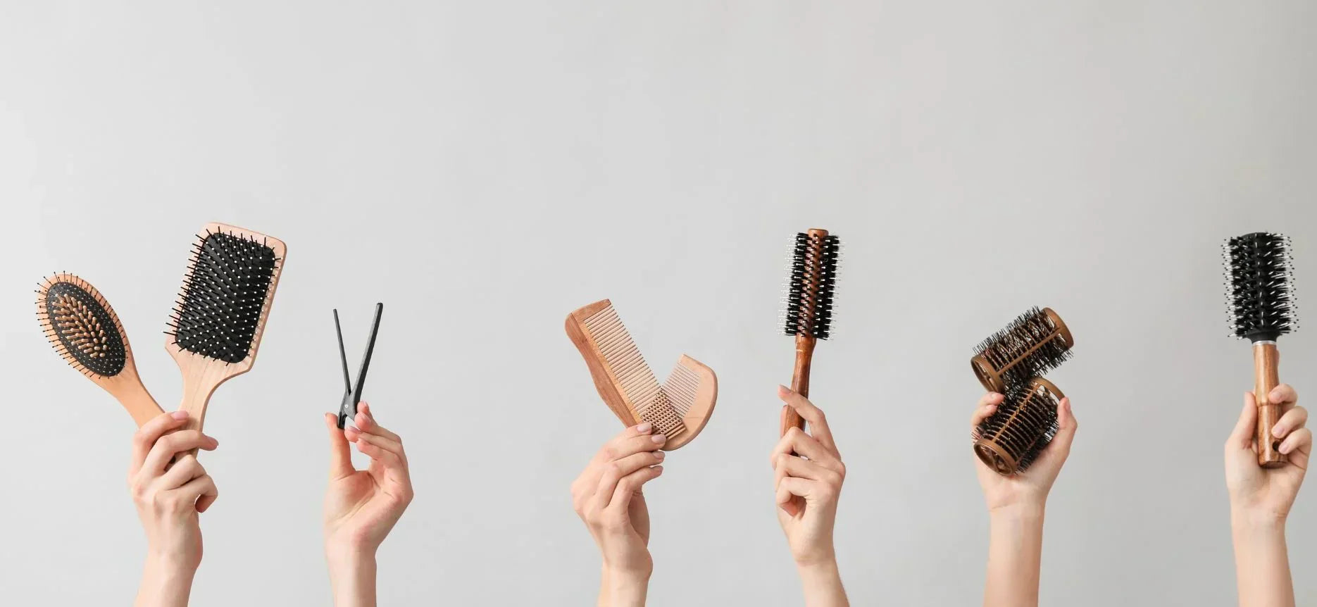 Hands displaying hair tools from the Silver Bullet collection against a light background.