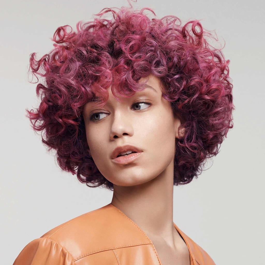 Vibrant magenta curly afro showcasing Goldwell Dualsenses Curls & Waves Hydrating Shampoo