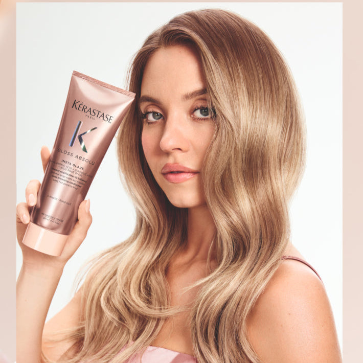 Woman holding a hair product with a soft, blurred background