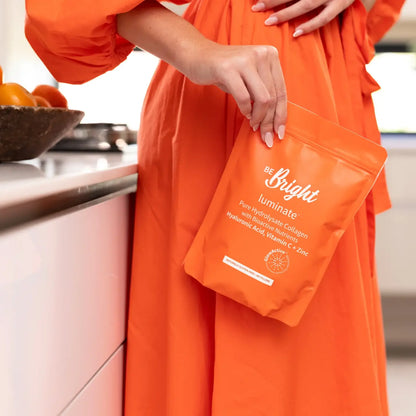 Orange coffee bag labeled Biftu held against an orange dress with Collagen Powder 650g