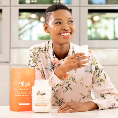 Be Bright Luminate: Hydrolyzed Collagen for Radiant Skin & Wellness. Woman drinking beverage near collagen powder.
