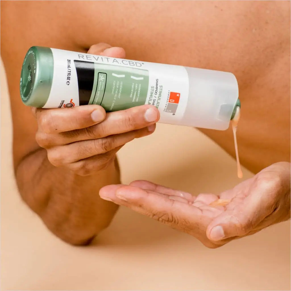 Cylindrical container of skincare or beauty product being dispensed onto a hand.