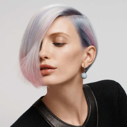 Woman with pastel-colored hair wearing a black top and dangling earring.